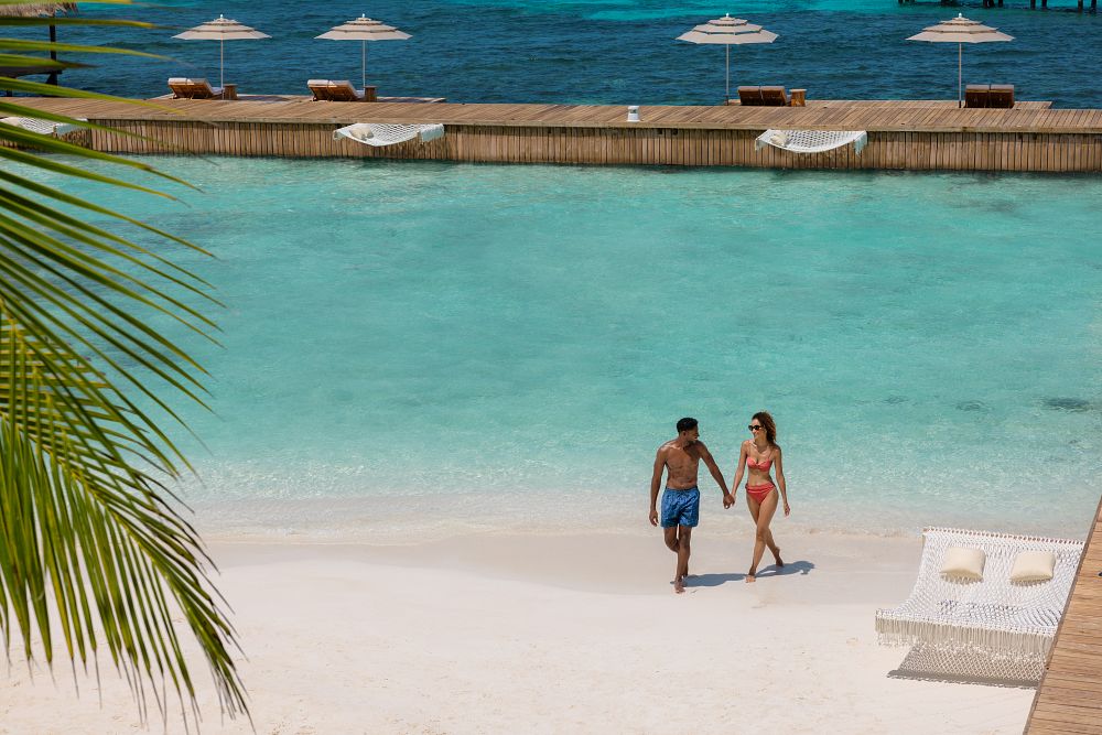 Couple walking hand in hand on a white sand beach